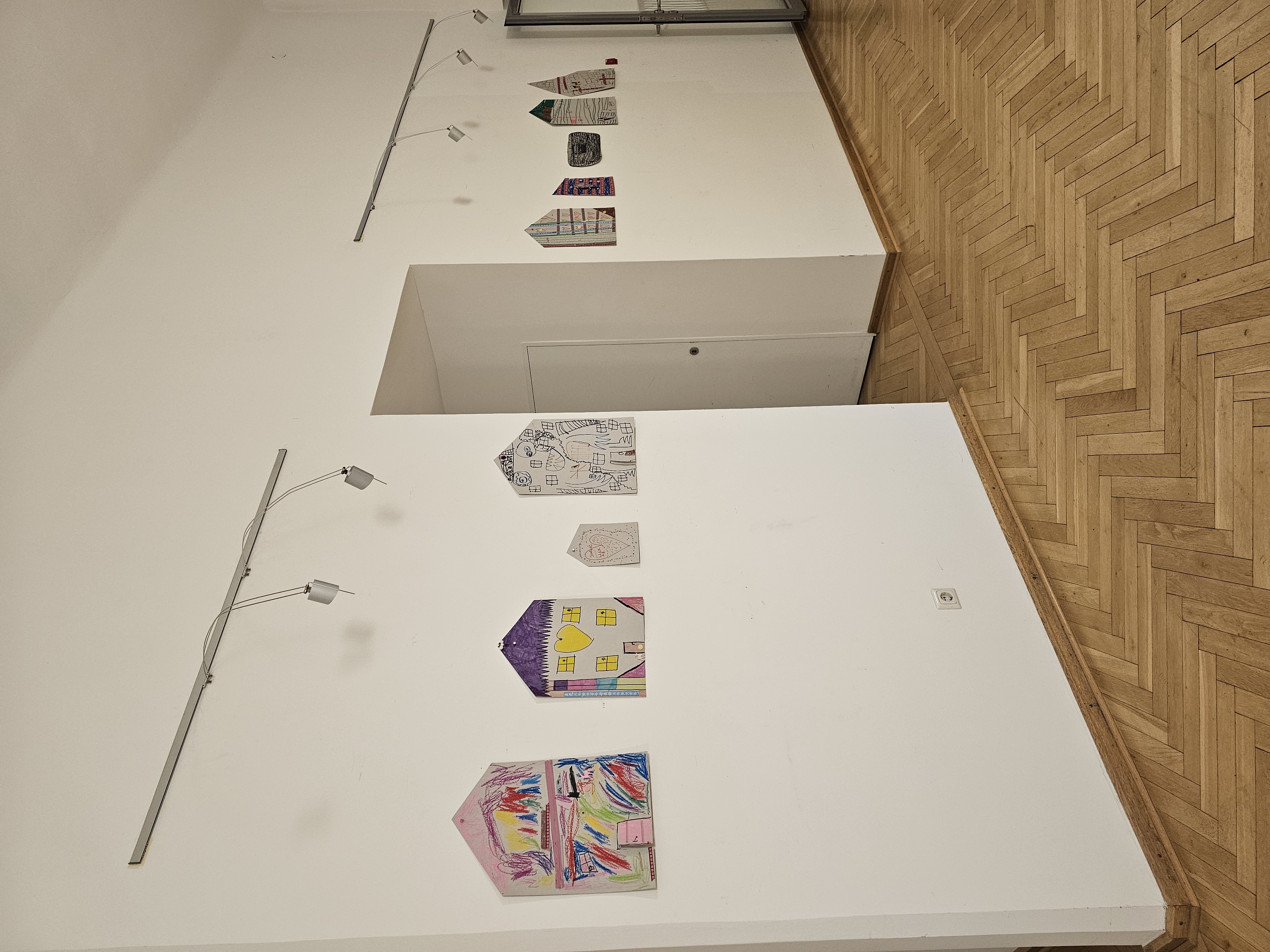 Ausstellung von Kinderbildern an einer weißen Wand