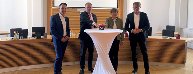 Christian Dutz, WeLocal World AG, Bezirkstagspräsident Henry Schramm, Regierungspräsidentin Heidrun Piwernetz und TVO-Geschäftsführer Norbert Kießling beim symbolischen Freischalten der Oberfranken-App. Der Bezirkstagspräsident Henry Schramm und die Regierungspräsidentin von Oberfranken Heidrun Piwernetz drücken einen großen roten Knopf als symbolischen Startschuss für die Oberfranken-App