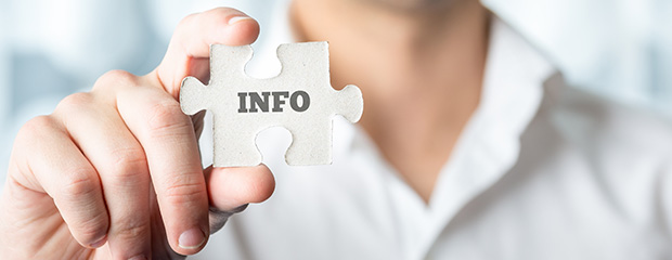 Symbolfoto Information: Frau in weißer Bluse hält ein Puzzleteil mit dem Wort "Info" hoch